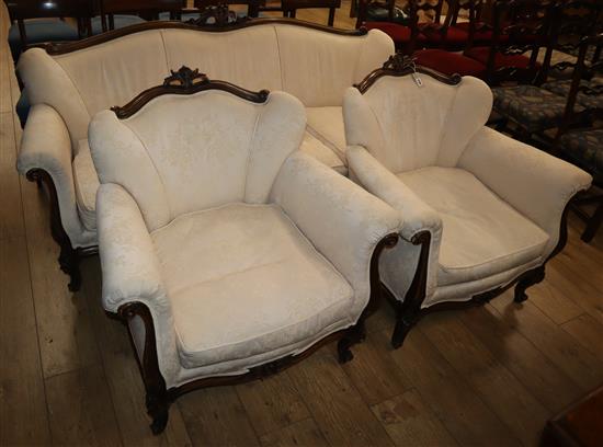 An early 20th century French carved mahogany three piece suite, upholstered in ivory damask